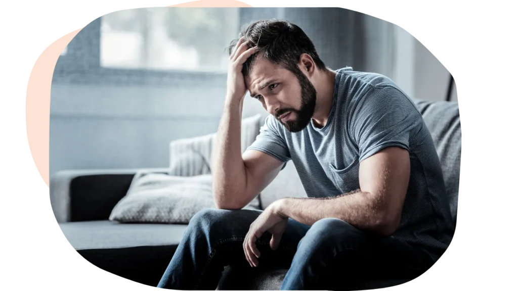 A man with anxiety holding his head and looking stressed